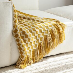 Mustard yellow and ivory knitted throw blanket with a zig-zag pattern and tassels,