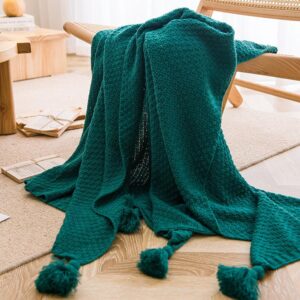 Green knitted throw blanket with tassels.
